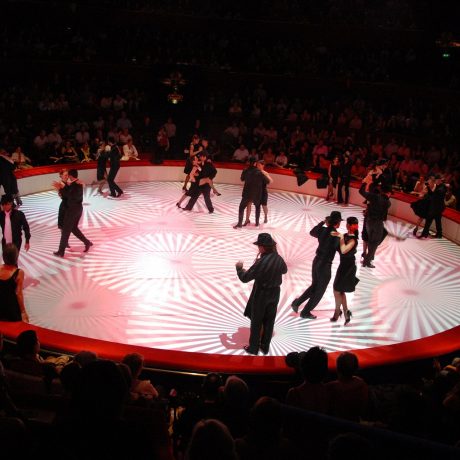 De nombreux couples qui dansent le tango dans une scène circulaire